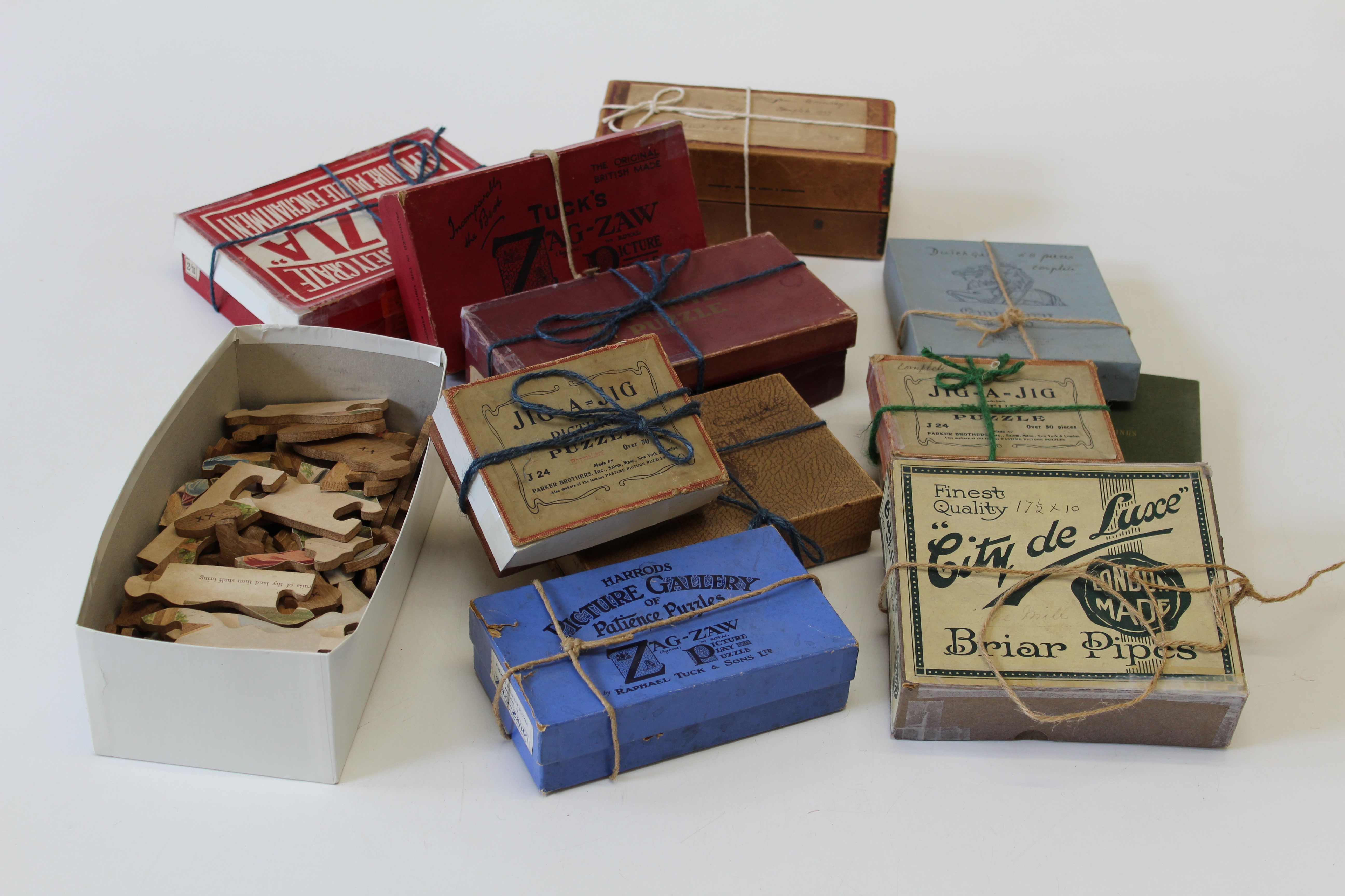 A collection of thirteen early 20th century hand cut wooden jigsaw puzzles, including Parker