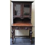 A late 19th century carved oak side cabinet, having a pair of half length glazed panel doors, over a