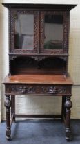 A late 19th century carved oak side cabinet, having a pair of half length glazed panel doors, over a