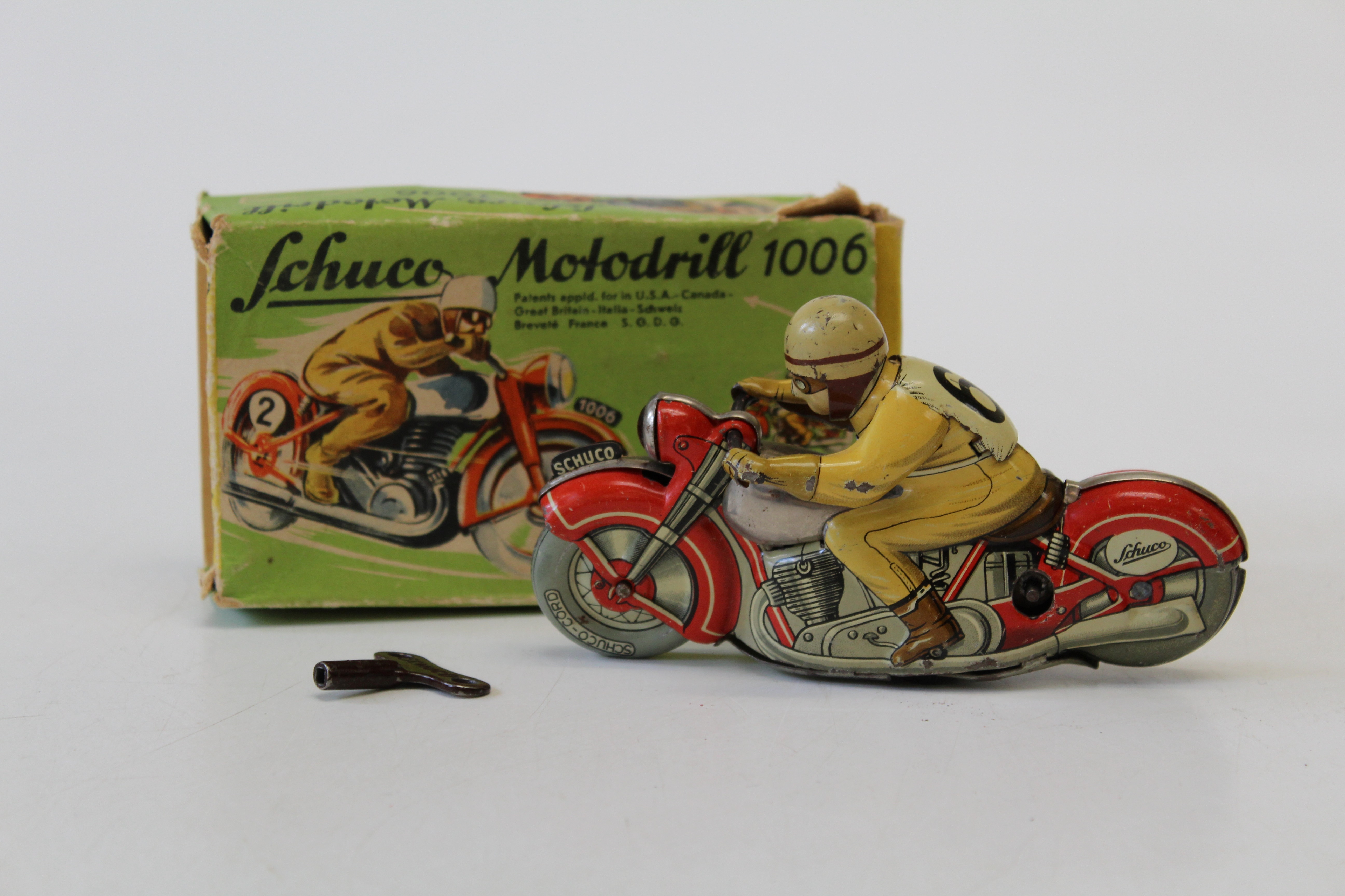 A boxed Schuco Motodrill 1006 tinplate clockwork motorcycle, rider number 6 with red motorcycle,