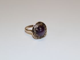 A star sapphire cocktail ring. Set with a purple star sapphire, in claw setting above an openwork