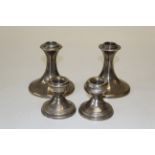 Two pairs of silver dwarf candlesticks, the first of outswept faceted form, by William Comyns,