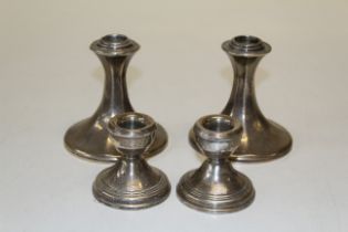 Two pairs of silver dwarf candlesticks, the first of outswept faceted form, by William Comyns,