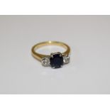 A diamond and sapphire three stone ring in 18ct yellow gold featuring a central oval, sapphire and
