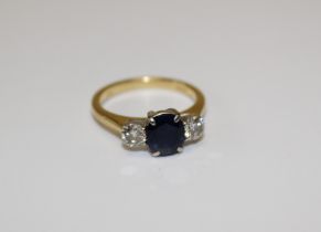 A diamond and sapphire three stone ring in 18ct yellow gold featuring a central oval, sapphire and
