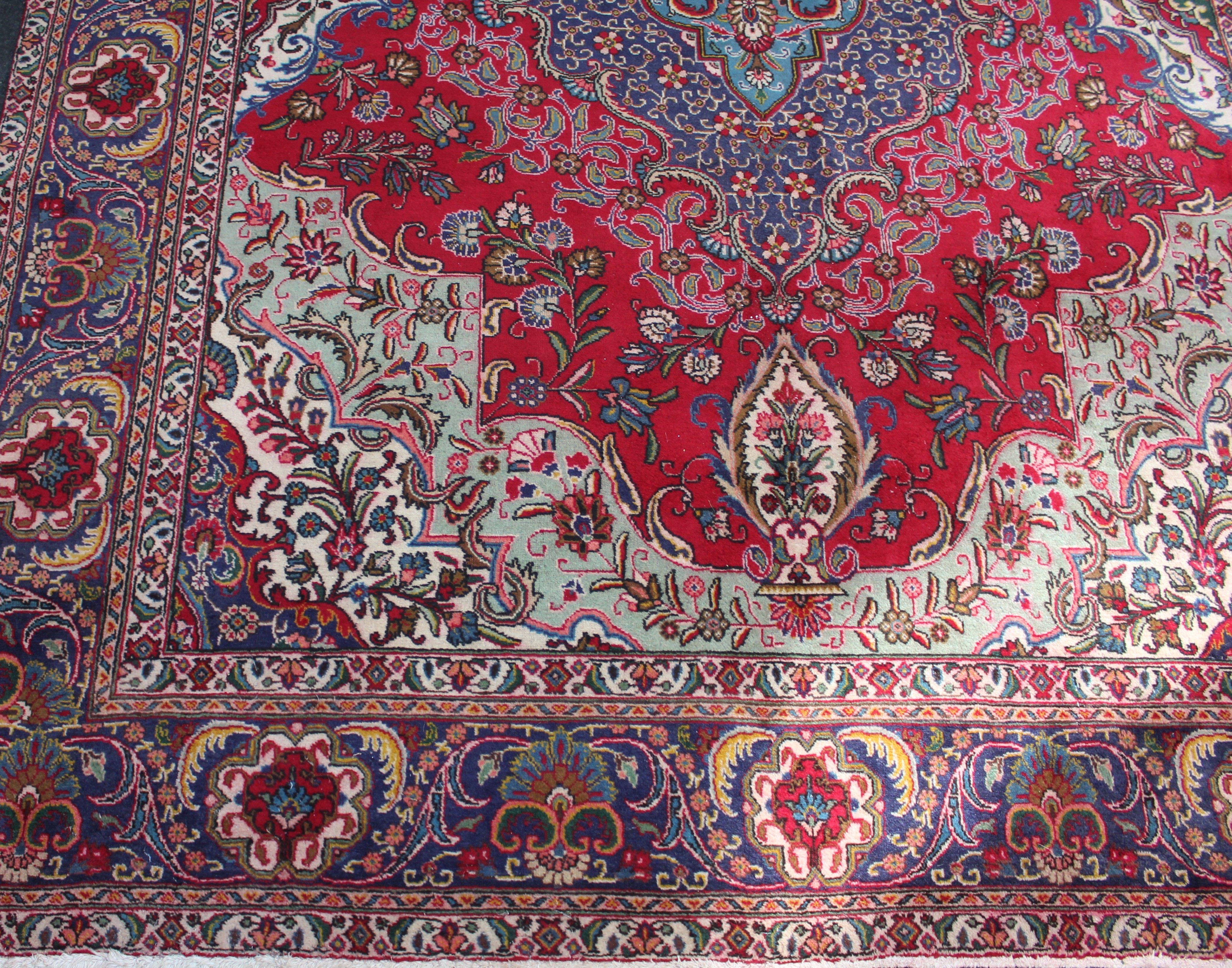 A 20th Iranian wool carpet, woven with a stepped central floral medallion on a predominantly red