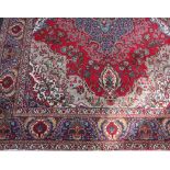 A 20th Iranian wool carpet, woven with a stepped central floral medallion on a predominantly red
