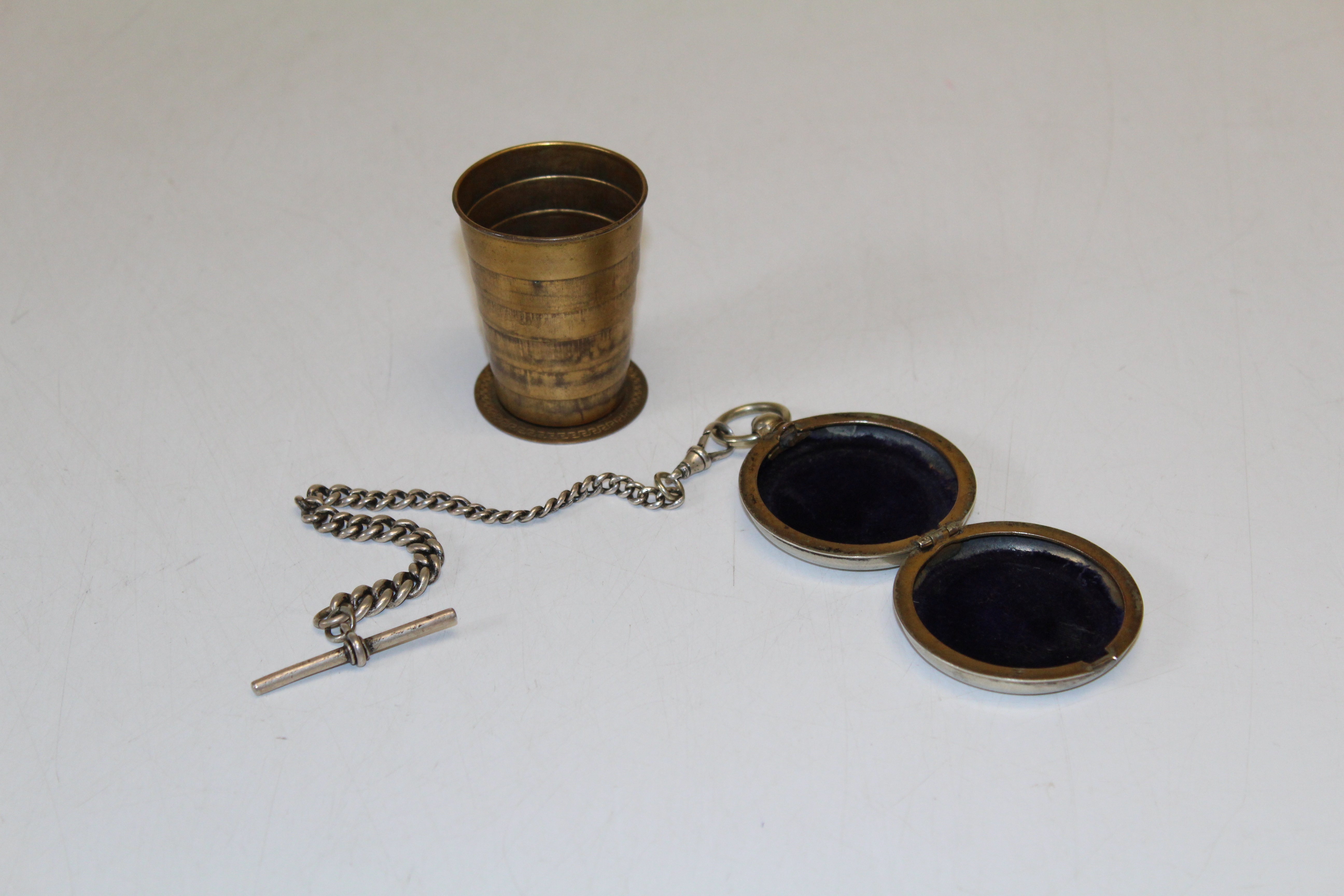 Collapsible cup into a pocket watch case with a silver Albert watch chain. Patent number I5061