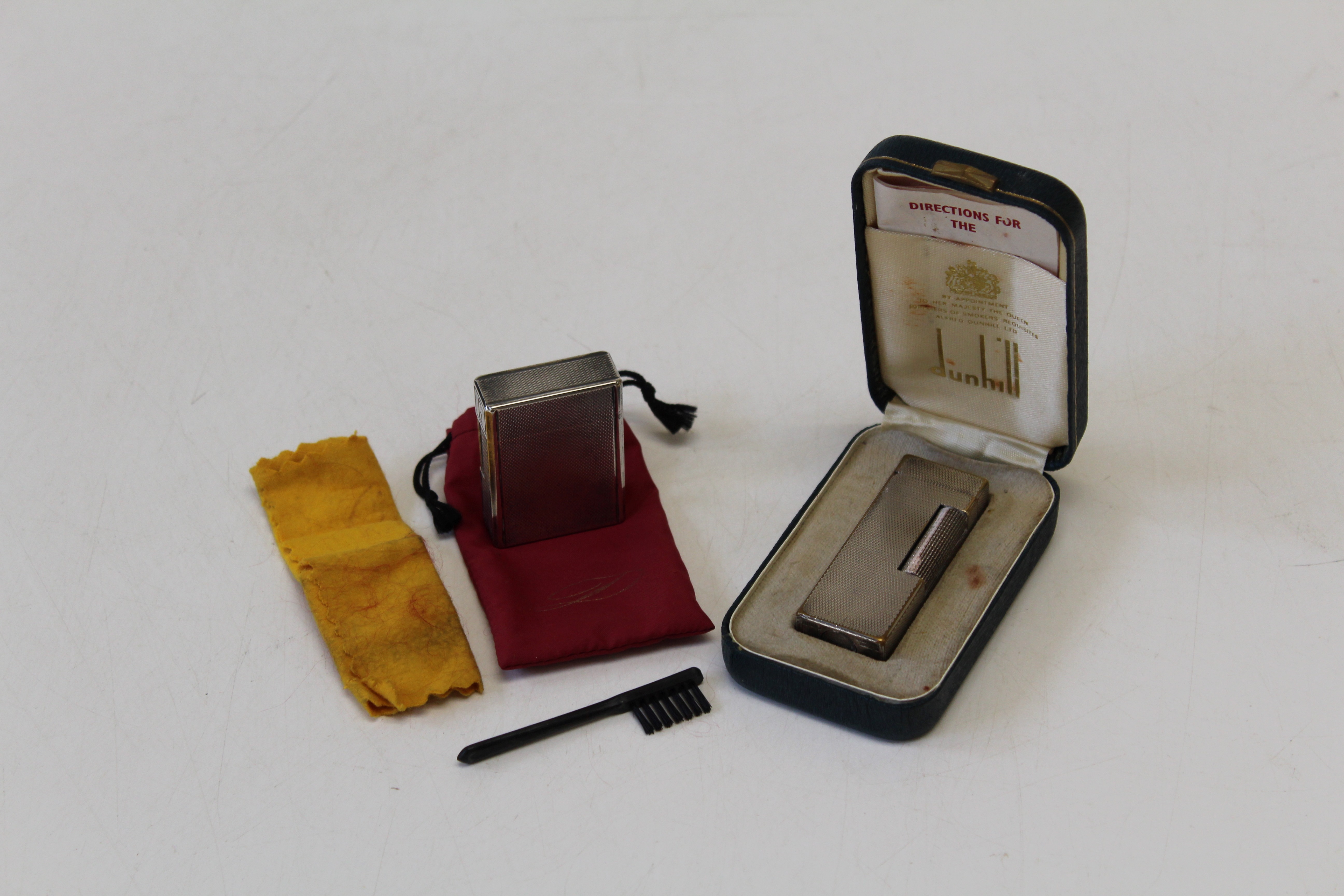 A cased silver plated Dunhill Rollagas lighter, together with another by Dupont. Both with engine