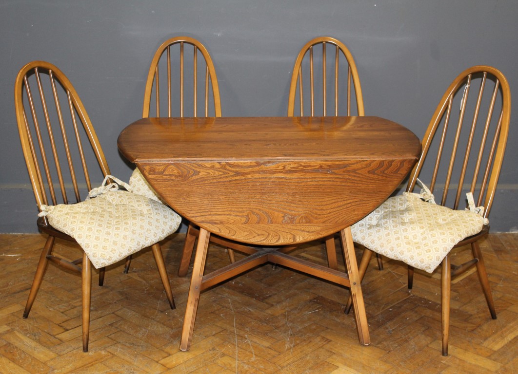 An Ercol light elm drop flap dining table, the oval top raised on fluted splayed square supports,
