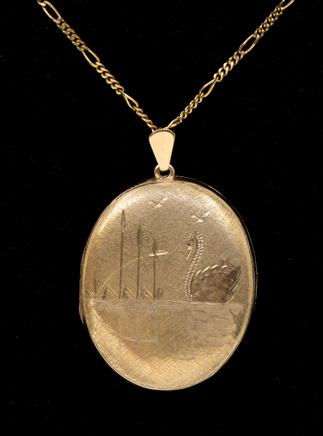 A 9ct gold oval locket, engraved, depicting river scene with a swan, length approx 38mm, suspended