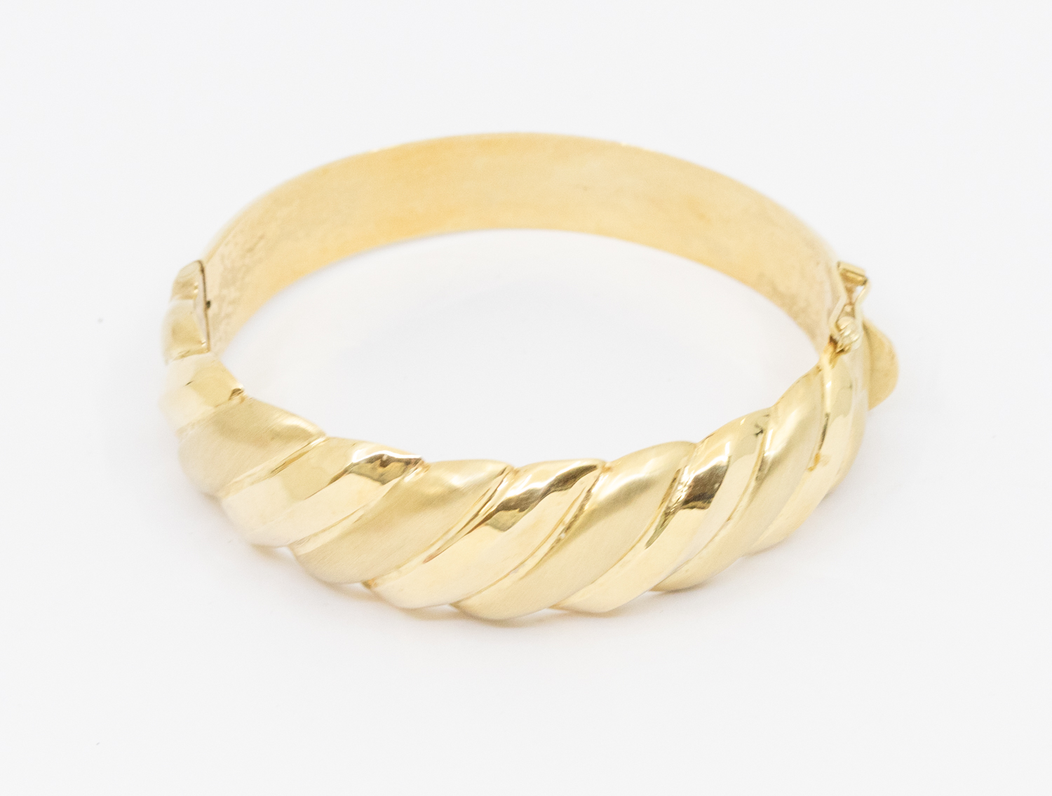 A 14ct gold hollow hinged bangle, comprising ridged matt and polished sections, width approx 18mm,