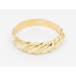A 14ct gold hollow hinged bangle, comprising ridged matt and polished sections, width approx 18mm,