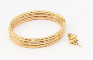 A 9ct gold tri colour hollow bangle, comprising three gold textured rows, width approx 12mm, (some