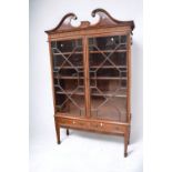 A George III mahogany glazed book cabinet with scrolled pediments, inlaid finish, mostly original