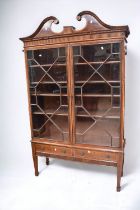 A George III mahogany glazed book cabinet with scrolled pediments, inlaid finish, mostly original