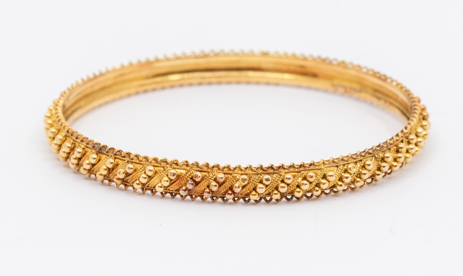 A 22ct gold bangle with popcorn style decoration, width approx 6mm, internal diameter approx 62mm,