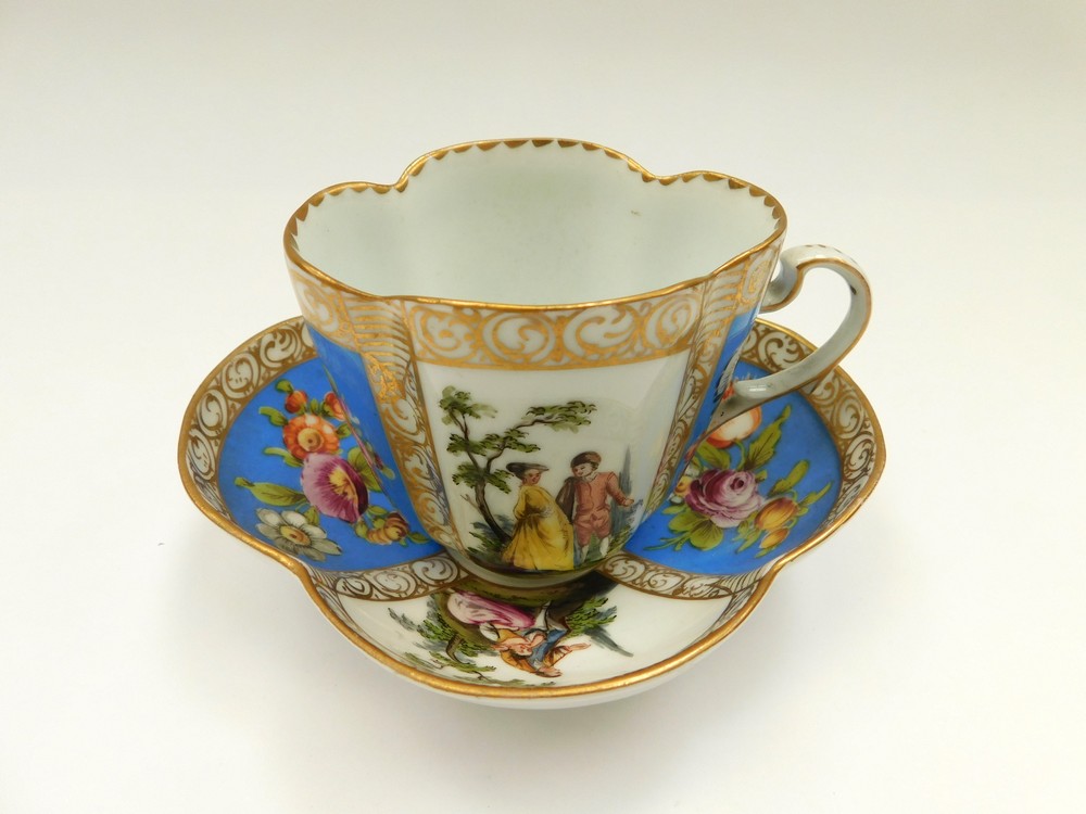 A Dresden quatrefoil cup and saucer with two blue panels painted with floral sprays and two panels