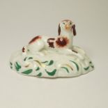 A small figure possibly Rockingham of a spaniel laying on a rocky mound base. Circa; 1830 Size;
