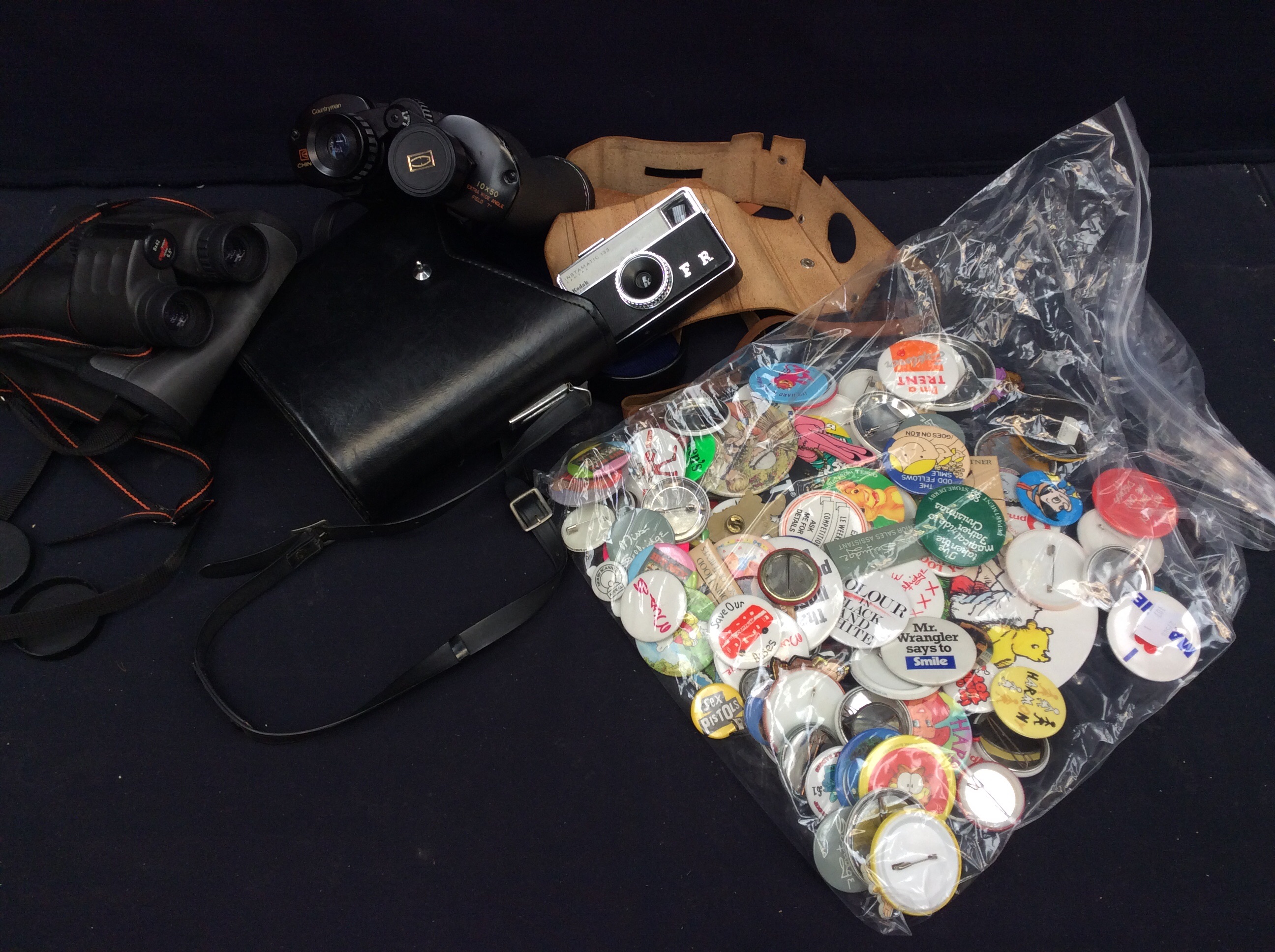 Two pairs of binoculars, vintage camera and a collection of vintage pin badges.