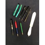 A collection of mid 20th Century pens along with a mother of pearl page turner.