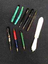 A collection of mid 20th Century pens along with a mother of pearl page turner.