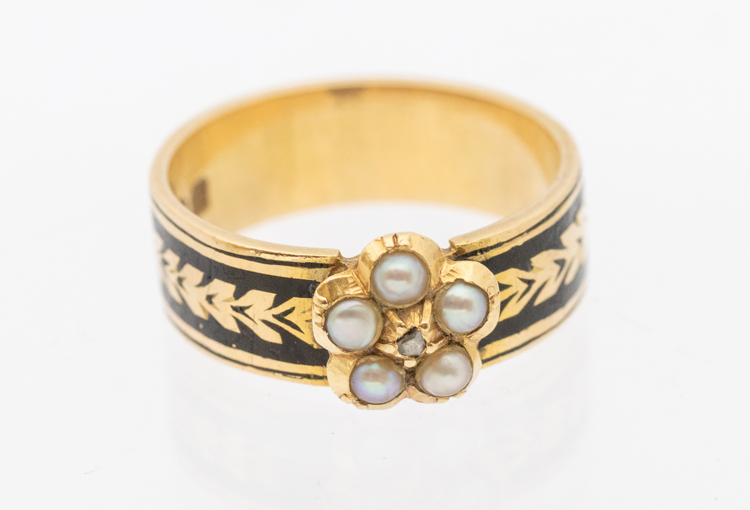 An enamel and seed pearl ring, with daisy pearl and diamond set motif to the front, the band with