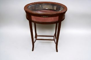 An Edwardian oval glazed with inlayed top collectors cabinet on sabre legs.