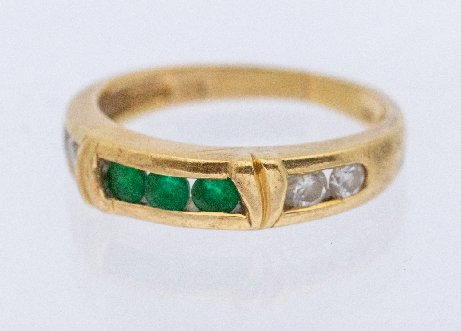 An emerald and diamond ring, comprising a central channel set row or three round mixed cut emeralds,