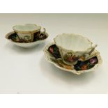 Two cups and saucers, one with AR mark for Augustus Rex with two black panels with floral sprays and