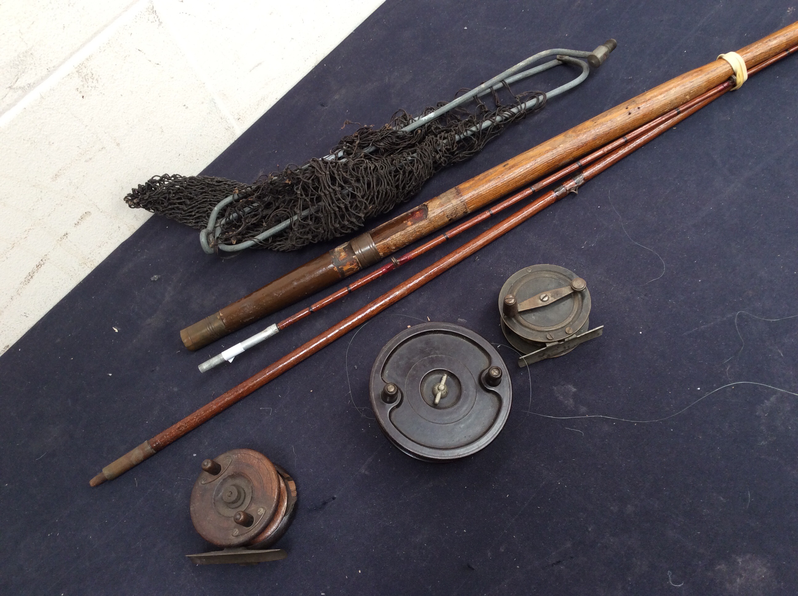 Three early 20th Century fishing reels with nets along with an early 20th Century cane fishing rod.