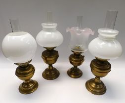 Four late 19th Century/early 20th Century brass oil lamps with shades.