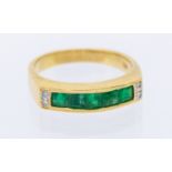 An emerald and diamond 18ct gold ring, comprising a channel et row of calibre cut emeralds, with