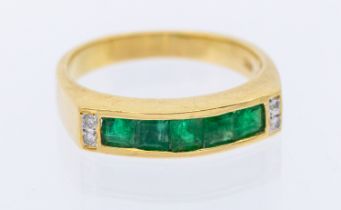 An emerald and diamond 18ct gold ring, comprising a channel et row of calibre cut emeralds, with