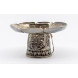 An Asian white metal (untested) altar bowl stand embossed with floral and motif decoration and