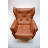 An early 1970s teak and leatherette button back lounge armchair on castors.
