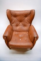 An early 1970s teak and leatherette button back lounge armchair on castors.