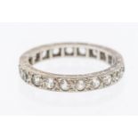 A stone set white metal eternity ring, width approx 3mm, size K1/2, unmarked, engraved mount,