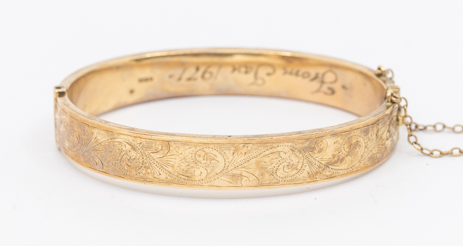 A 9ct gold hollow hinged bangle, engraved decoration to top, width approx 10mm,  inscription to