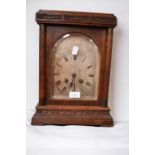 A 19th Century oak eight day mantle clock with silvered arched dial and Roman numerals.