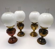 Four late 19th Century/early 20th Century brass oil lamps with shades.