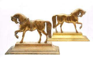 A pair of brass doorstops in the form of horses.