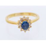 A sapphire and diamond 18ct gold cluster ring, set with an oval mixed cut sapphire approx 5x4mm,