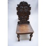 Early 19th Century oak hall chair with tall carved ornate back rest, on turned legs.