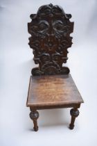 Early 19th Century oak hall chair with tall carved ornate back rest, on turned legs.