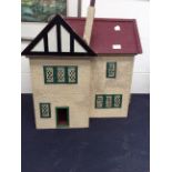 A 1920s dolls house with furniture, metal windows and rendered all around.