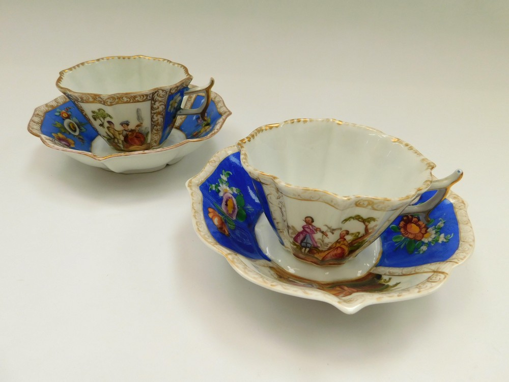 Two Dresden tea cups and saucers with two blue panels with floral sprays and two panels with