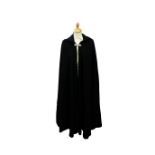 A black wool opera cape with brass leaf motif fastening, with a hood.