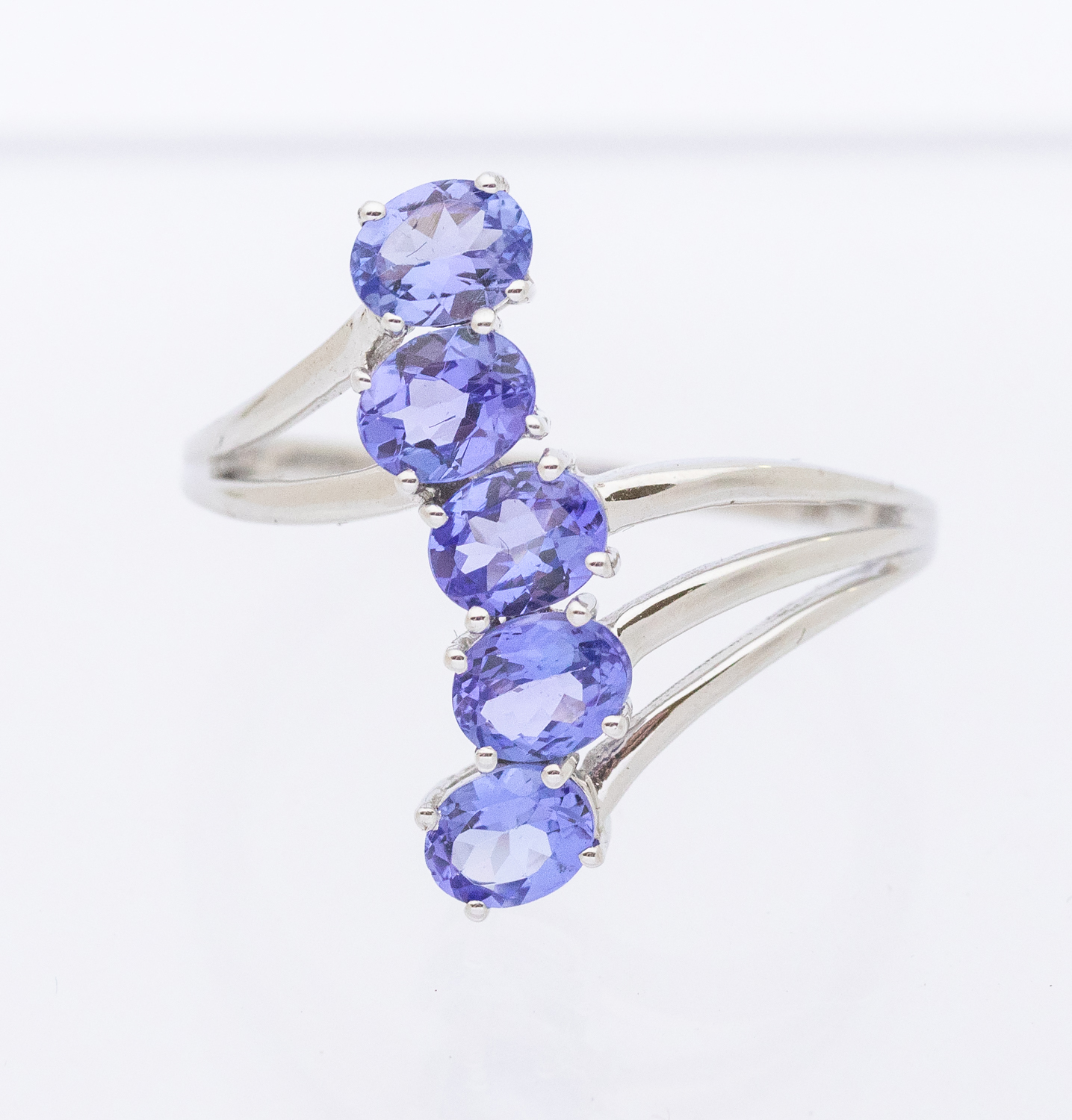 A tanzanite and 9ct white gold ring, comprising a row of five oval mixed cut stones, claw set to a