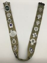A webbing belt, fitted with numerous vintage chromed, enamelled, examples of police constabulary